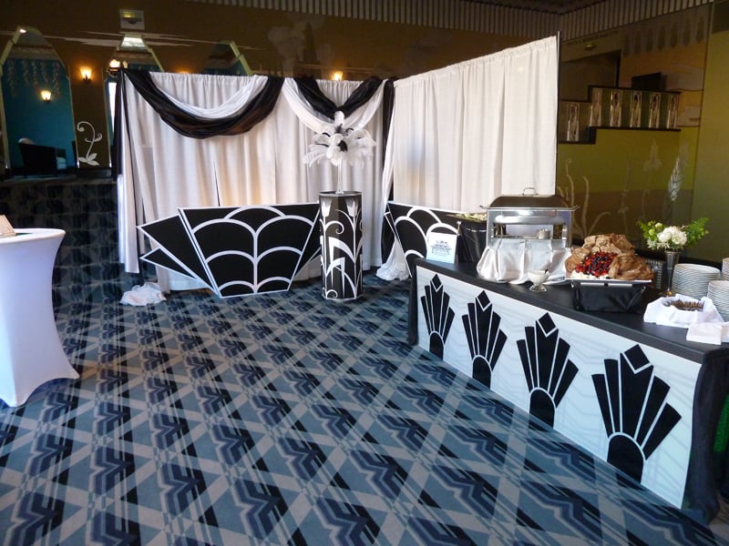 Black-and-white Art Deco panels, drapery and feather accents frame an event buffet.