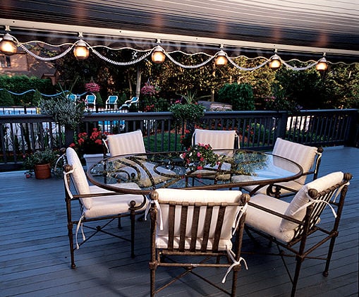 Six hanging canopy lanterns above a patio dining table and chairs on an outdoor deck.