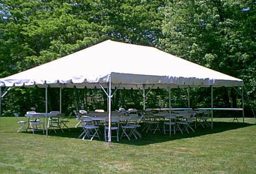 A white rectangular event canopy with a scalloped valance, round tables and white folding chairs on a lawn.