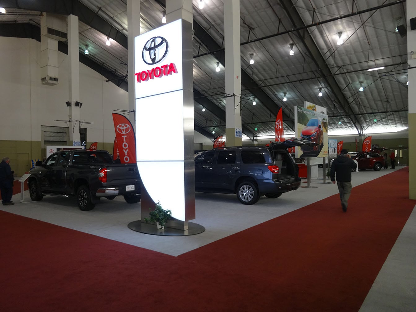 An illuminated Toyota sign, vehicles and carpeted aisles at the 2017 auto show.