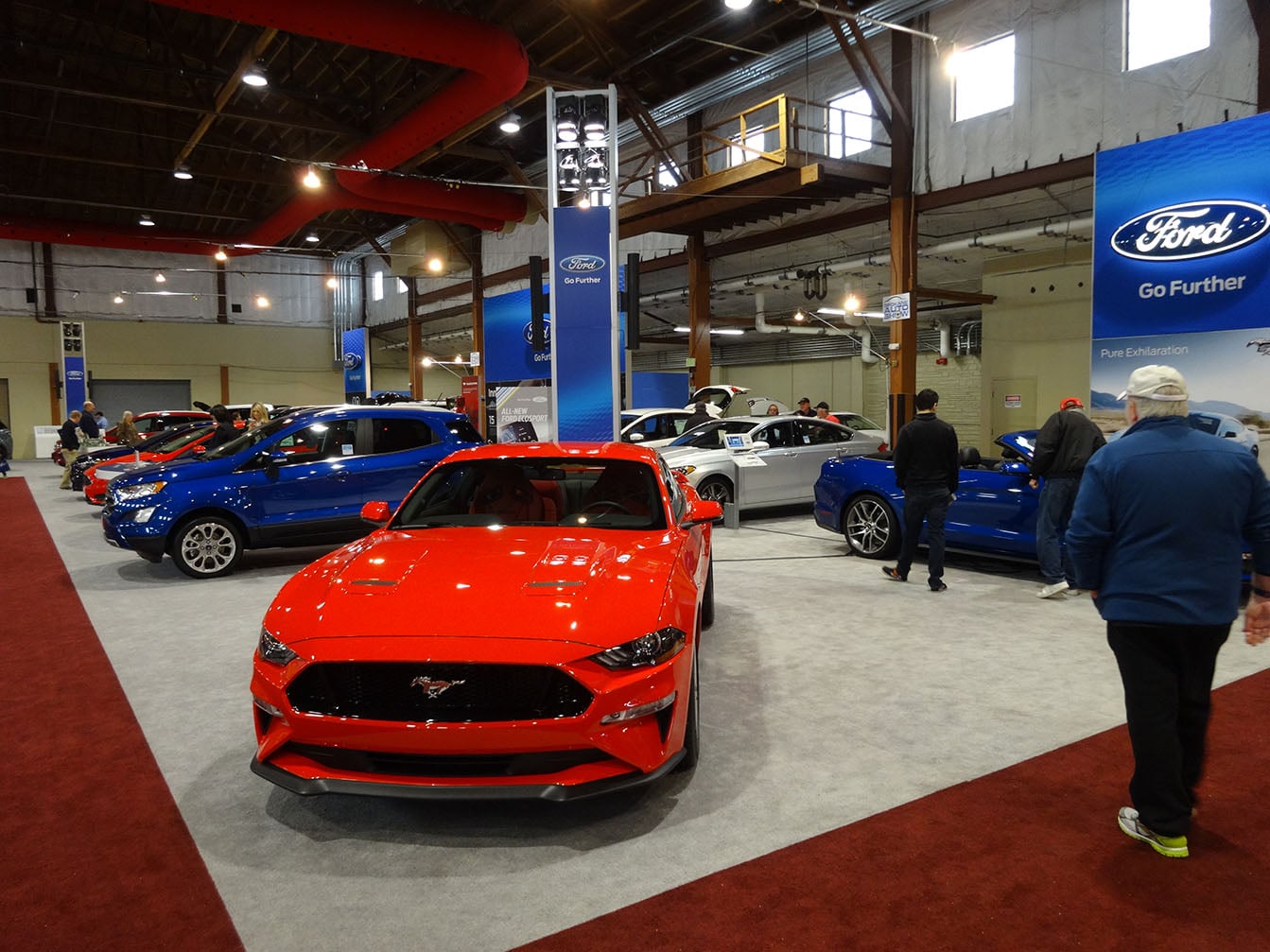 A red Mustang and other Ford vehicles with exhibit banners at the 2017 auto show.