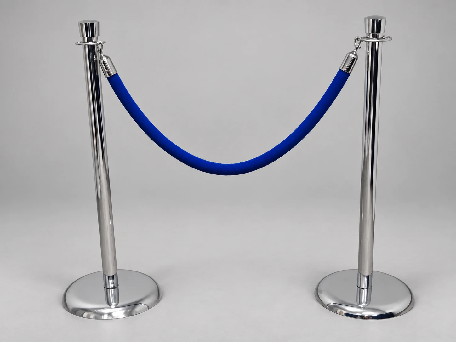 Two chrome rope stanchions with round bases and a blue velvet rope.