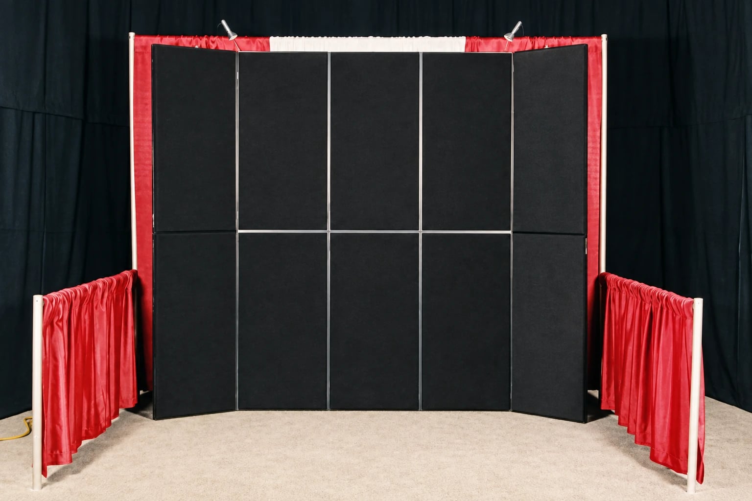 A black five-panel rental display with two top lights, a red and white drape border and red side drapes.
