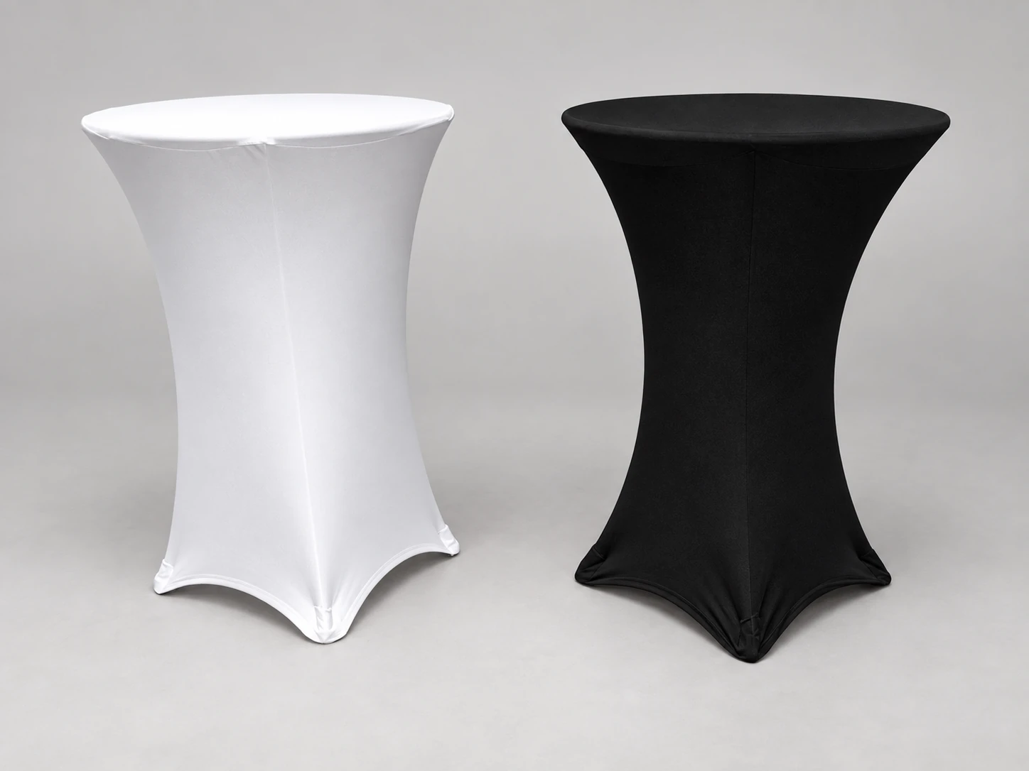 White and black stretch-fabric cocktail tables on a neutral studio background.